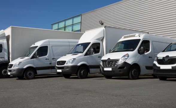 A fleet of commercial vehicles, including vans, trucks, and cars, parked in front of an Insurance Agency in Dayton, Ohio, representing commercial auto insurance services.